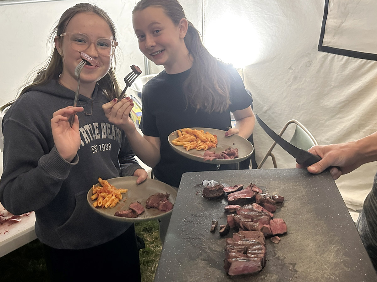 Two youth hunters with smiles on their faces try eating deer heart